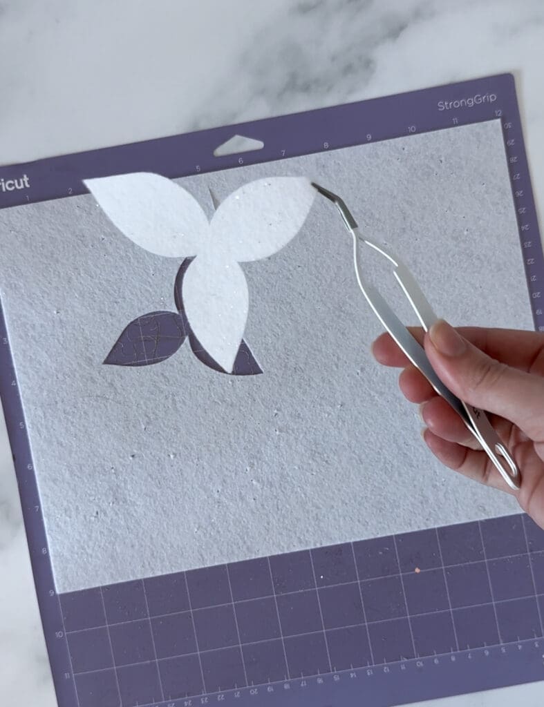 Pulling cut flower shapes off of Cricut mat using tweezers