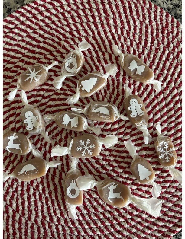 Caramels scattered on red and white mat with cricut cut shapes on wrappers