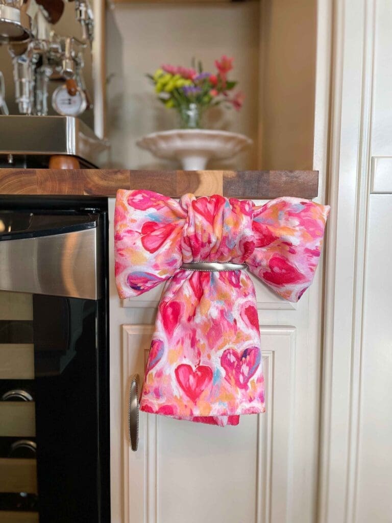Valentine's Day dish towel made into a bow shape through a kitchen drawer handle