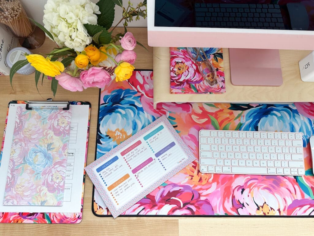 Colorful desktop featuring painted peonies products by Zappy Dots, and a weekly planner pad with hand-written details. 